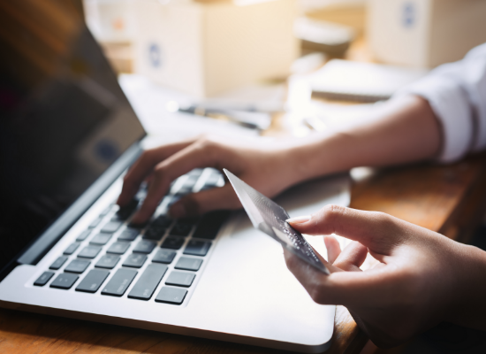 Hand holding credit card over laptop Hand holding credit card over laptop